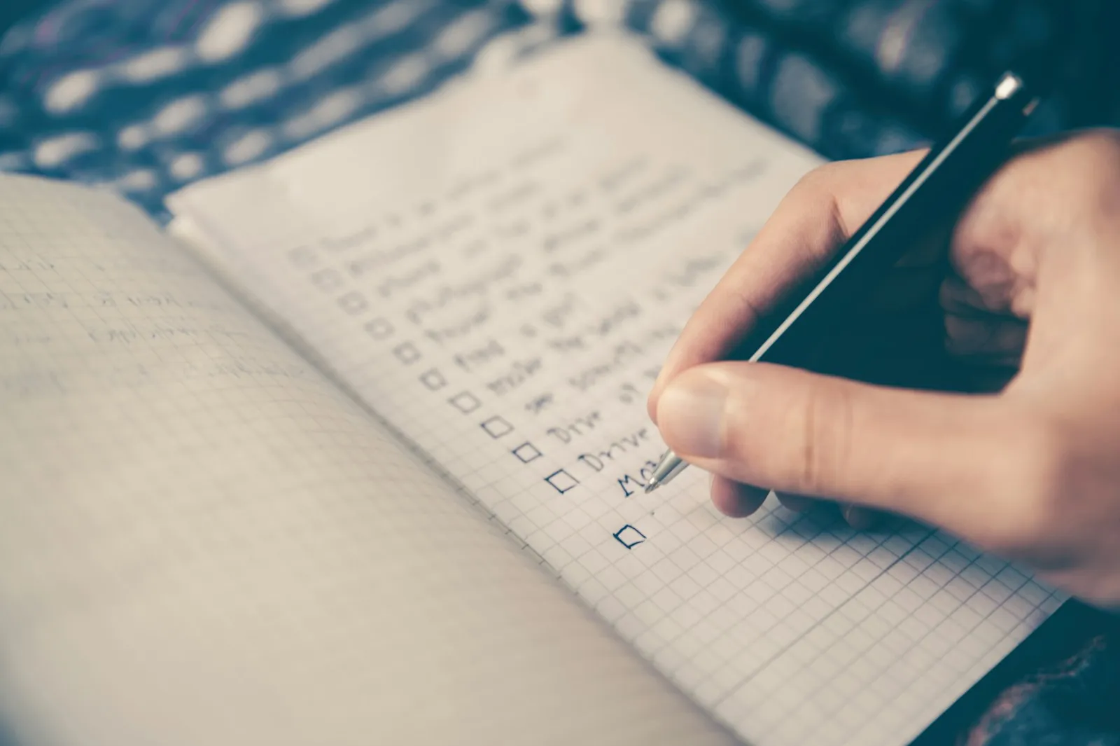 Person hält einen Stift über eine Liste in einem Notizbuch